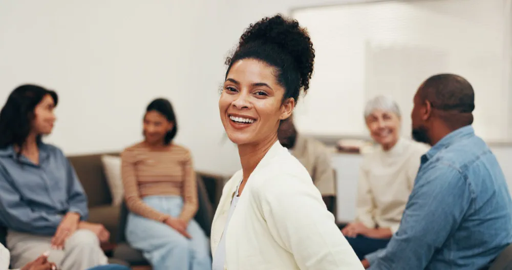 Woman smiling during a supportive mental wellness group session